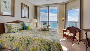 Una camera d'albergo con un letto grande, una sedia e vista sull'oceano.
