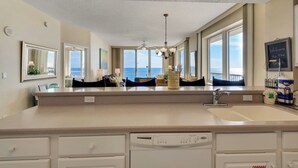Un'ampia cucina con un'isola grande, lavastoviglie e vista sul mare dalle finestre.