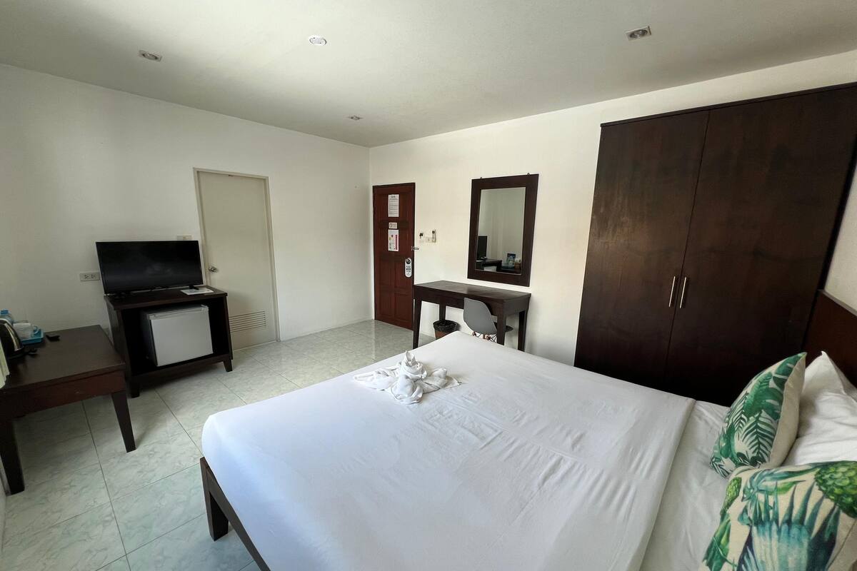 Een hotelkamer met een bed, een bureau, een televisie en een kledingkast.