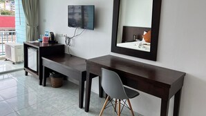 Ein Hotelzimmer mit Schreibtisch, Stuhl, Fernseher und einem großen Spiegel.