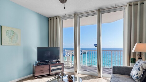 Een hotelkamer met balkon, televisie, bank en salontafel.