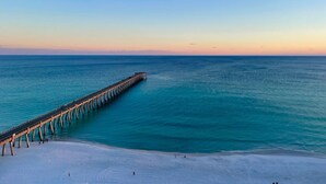 A pier extending into a calm sea with a beach in the foreground.