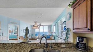 A kitchen with a double sink, granite countertop, and a coffee maker.