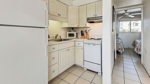 A compact kitchen with white cabinets, a microwave, an oven, and a sink. - Directly on the Gulf - Unit 14 - 1 Bedroom - Second Floor - Sleeps up to 5 (Venice)
