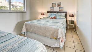 Un dormitorio con una cama, dos mesitas de noche, una ventana y vistas a edificios.