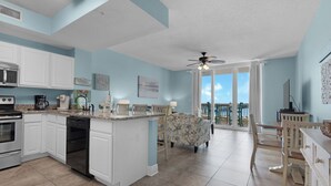 A kitchen with white cabinets, a microwave, and a coffee maker. There is a dining area with a table and chairs.