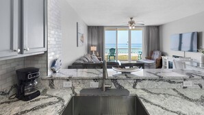 A modern kitchen with a marble countertop, a coffee maker, and a built-in sink.