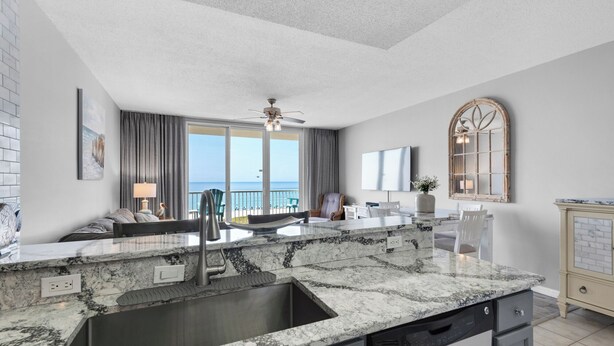 A modern kitchen with a large island, a built-in sink, and a view of the ocean.