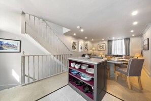 A modern interior with a staircase, dining area, and kitchenettes.