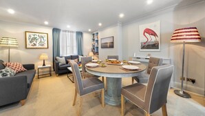 A modern living room with a round dining table, grey sofas, and a bookshelf. - Modern 3-floor open plan townhouse with patio (London)