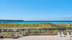 A beach with a pier, a walkway, and beach chairs. - Stow Away - Summerwind 101C (Navarre)