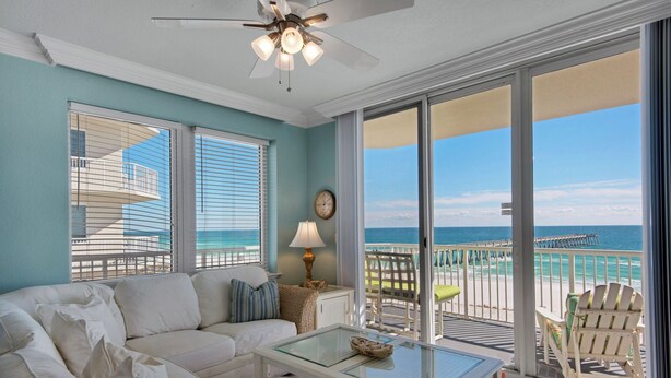 A room with a sofa, a glass-top table, and a view of the ocean through large windows. - Sanctuary - Summerwind 501C (Navarre)