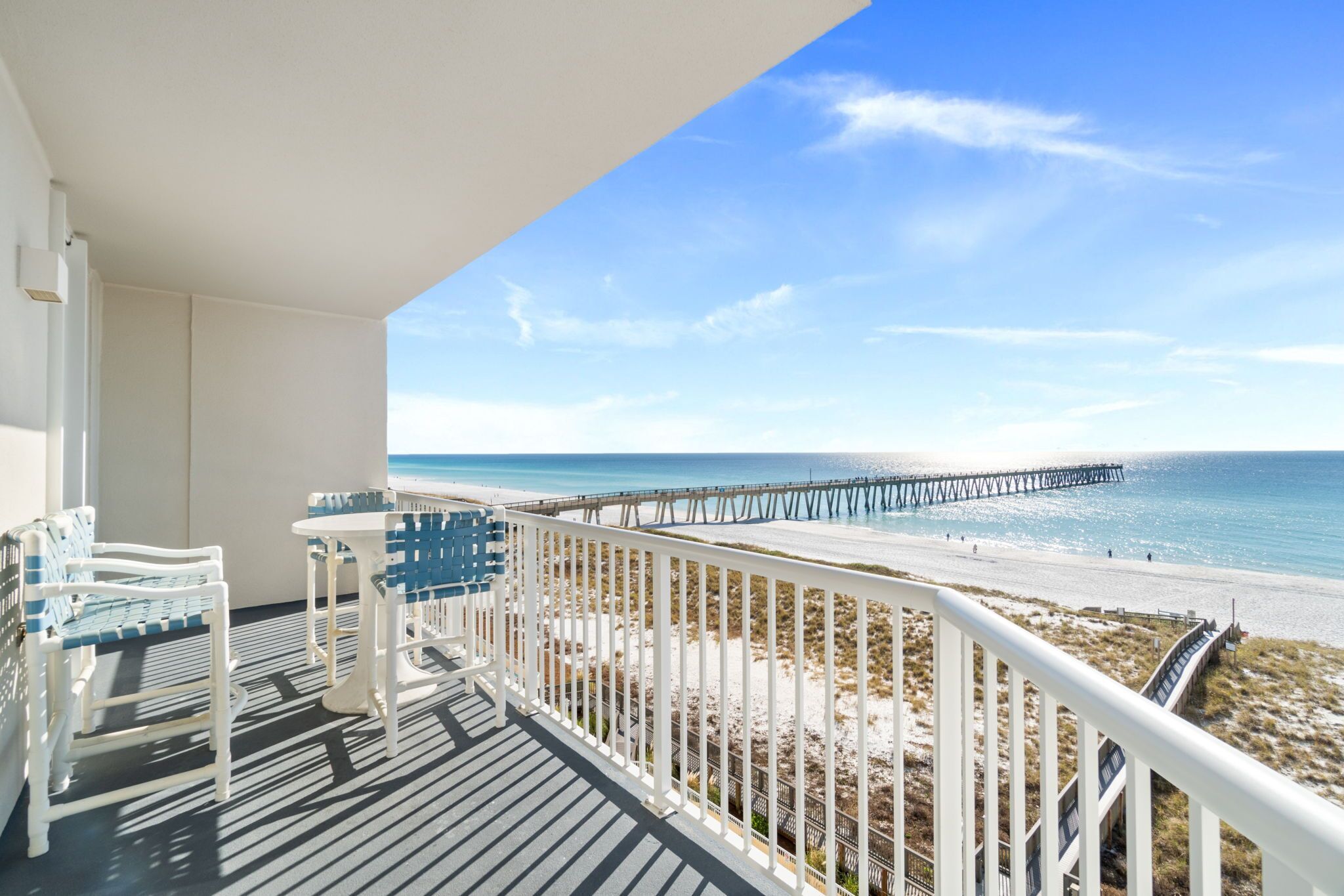 A balcony with a view of a beach and a pier.