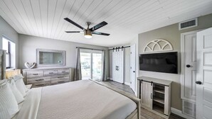 A bedroom with a bed, dresser, TV, and sliding doors. - PIECE OF SUNSHINE! 20% LOWER RATES NOW THROUGH THE END OF THE YEAR! (Navarre)