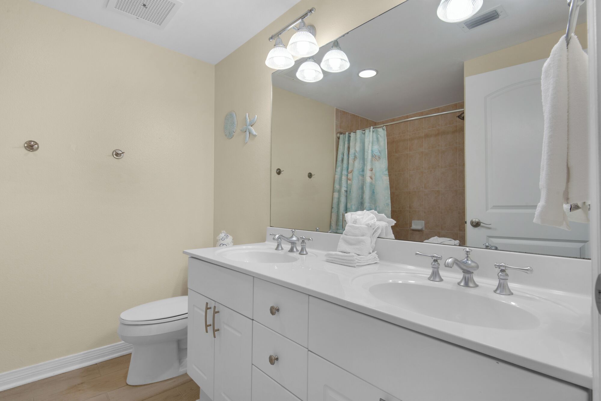 A modern bathroom with two sinks, a toilet, and a shower area.