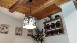 Teto de madeira com detalhes entalhados, luminária pendente e prateleira com pratos decorativos.