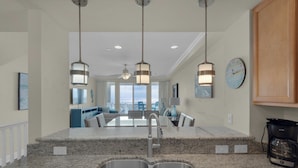 A modern kitchen with granite countertops, stainless steel sink, and pendant lighting.
