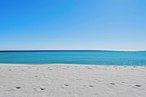 En strand med kristallklart blått vatten och vit sand.