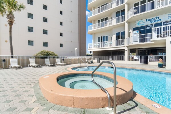 Une piscine avec un jacuzzi, des chaises longues et un bâtiment portant l’inscription « Magasin de plage ».