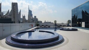 A rooftop pool area with a circular design, surrounded by modern buildings and a clear sky. - Charming Studio in Saba 3, Jumeirah Lake Tower by Deluxe Holiday Homes (Dubai)