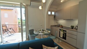 Un espacio habitable compacto con zona de comedor, kitchenette y balcón con silla y mesa.