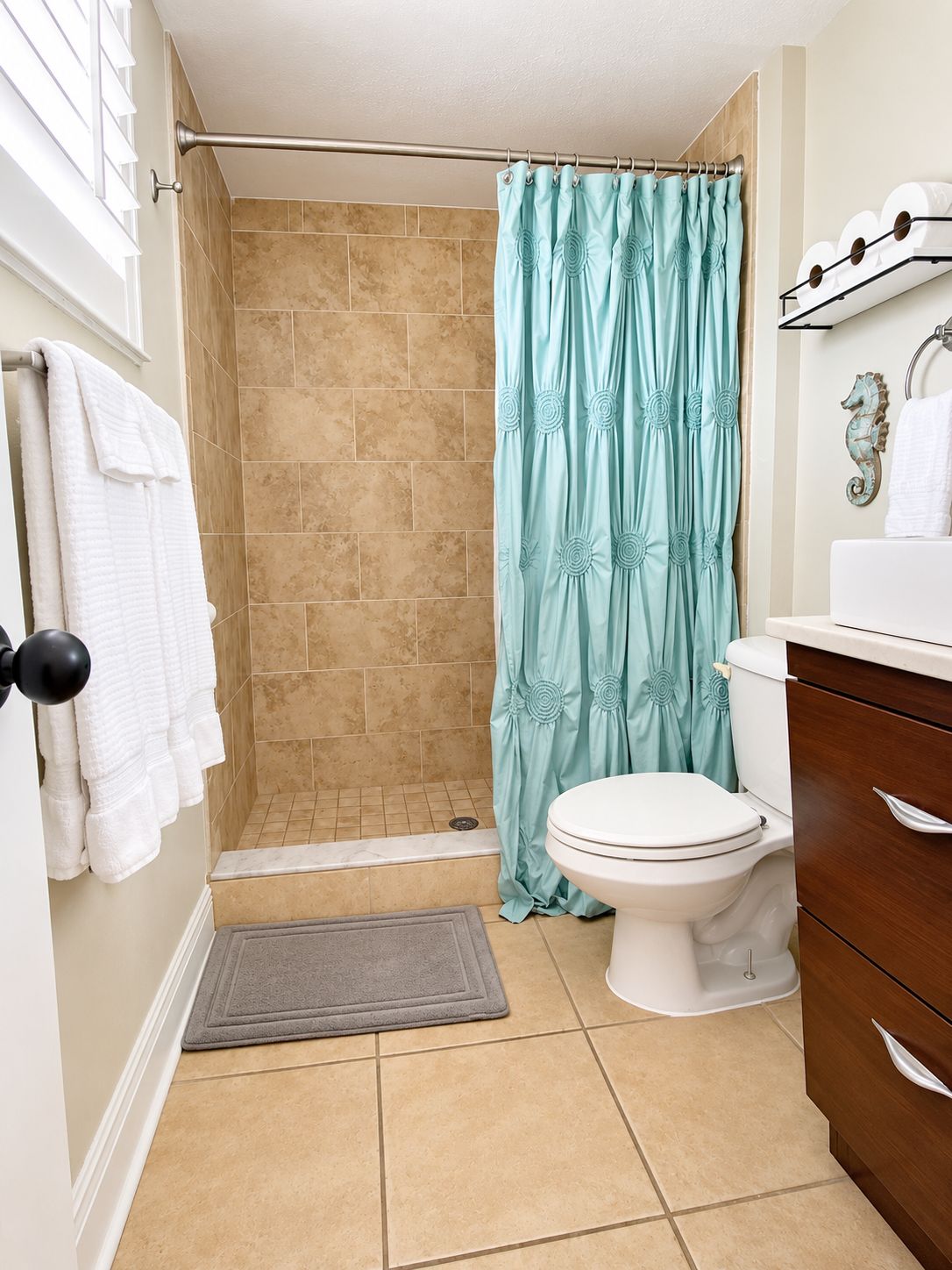 A bathroom with a shower, toilet, and a towel rack with towels.