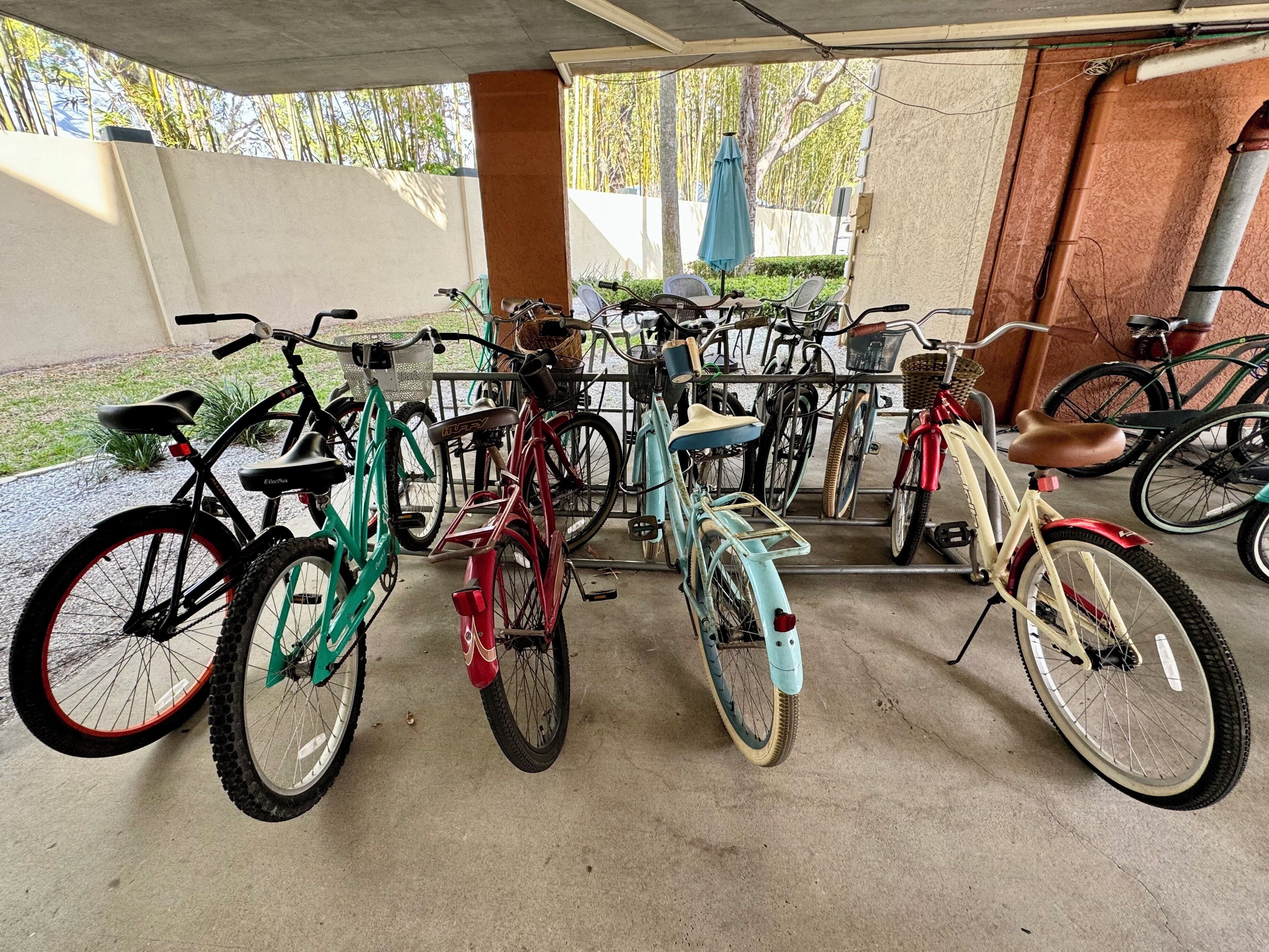 A covered bicycle parking area with various bicycles and a concrete floor.