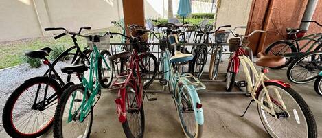 A covered bicycle parking area with various bicycles and a concrete floor.