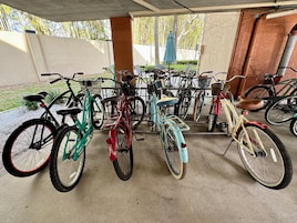 A covered bicycle parking area with various bicycles and a concrete floor.