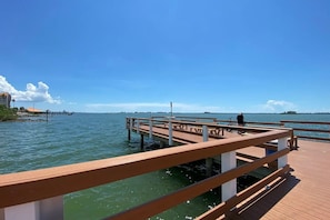 A wooden pier extending into calm waters with a clear sky.