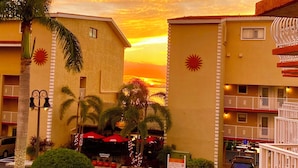 Un hotel con estacionamiento, palmeras y vistas al atardecer.