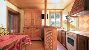 A wooden interior with a kitchen area, including cabinets, a stove, and a dining table with chairs. - 300m from ski slopes, 1st floor, parking, tv, 46m², Arêches-Beaufort (Beaufort)