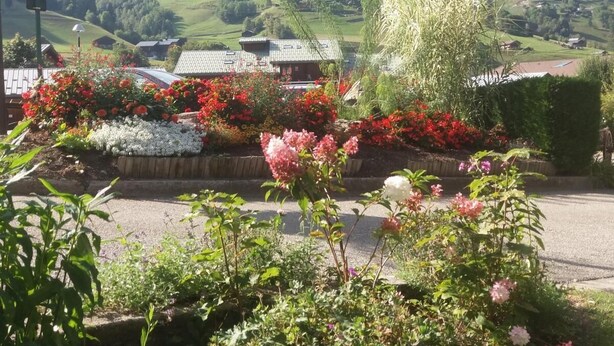 A rural landscape with a house surrounded by colorful flower beds and a view of rolling hills in the background. - 300m from ski slopes, 1st floor, parking, tv, 46m², Arêches-Beaufort (Beaufort)