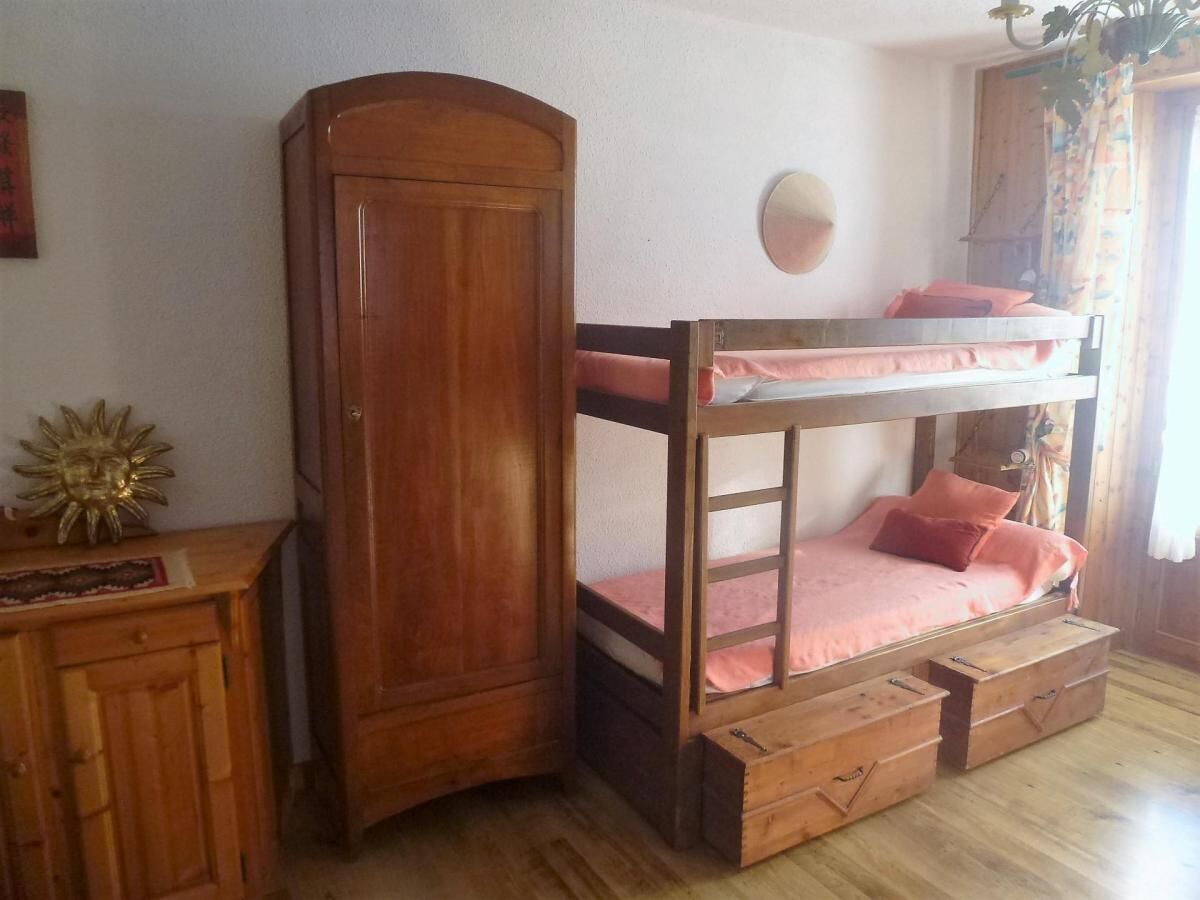 A bunk bed with a wooden wardrobe and a small cabinet.