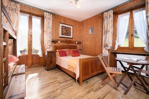 Ein Zimmer mit Holzboden, einem Bett, einem Schreibtisch und einem Stuhl.