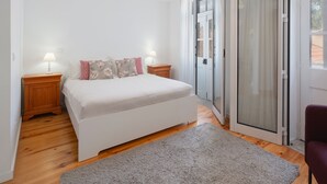 A bedroom with a bed, two bedside tables with lamps, a grey rug, and a red chair.