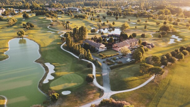 Eine Vogelperspektive auf einen Golfplatz mit Clubhaus, Teichen und umgebender Vegetation.