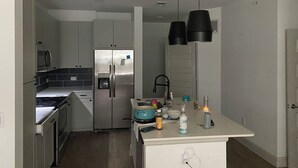 Cozinha moderna com eletrodomésticos de aço inoxidável, forno embutido e uma ilha central com diversos objetos.