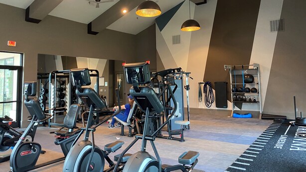 Uma academia com diversos equipamentos de exercícios, incluindo esteiras, aparelhos de musculação e um remo.