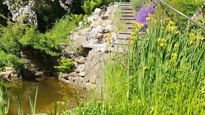 A garden with a pond, rocks, and various plants. - Schöne 120 qm Ferienwohnung + 50 qm Sonnenterrasse im Grünen-stockelsdorf/lübeck (Stockelsdorf)