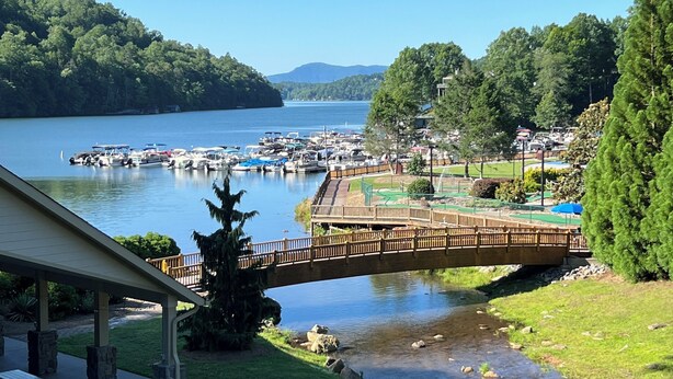 A lakeside view with a dock, picnic tables, and a small bridge.
