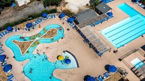 An aerial view of a pool area with multiple swimming pools, lounge chairs, and umbrellas.