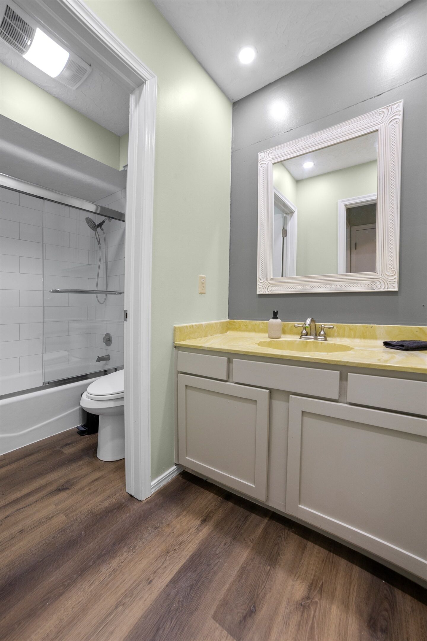 A bathroom with a shower, toilet, and vanity with a mirror.