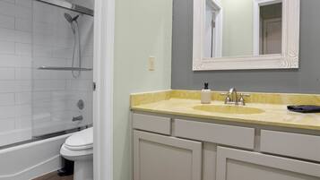 A bathroom with a shower, toilet, and vanity with a mirror.