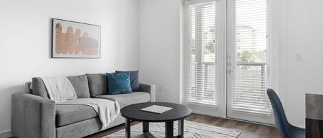 A modern living room with a grey sofa, a round black coffee table, and a white rug.