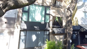 Een gebouw met een garagepoort, een balkon en een boom ervoor.