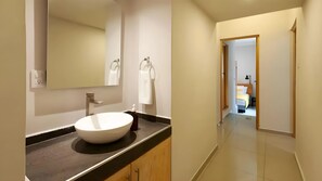 Un baño moderno con un lavamanos grande, un espejo y un perchero para toallas.