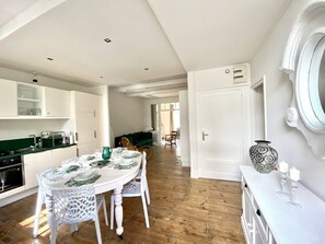 Spacious room with a dining area for four, featuring a white table and chairs, and a console table with decorative items.
