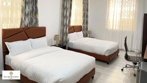 A hotel room with two beds, a ceiling fan, and a desk with a chair. - Villa Rio Boutique Hotel (Atimpoku)