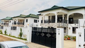 A row of white houses with green roofs and black gates. - Villa Rio Boutique Hotel (Atimpoku)